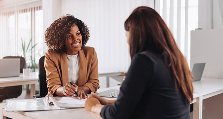 Two women sitting at a desk in a bank.